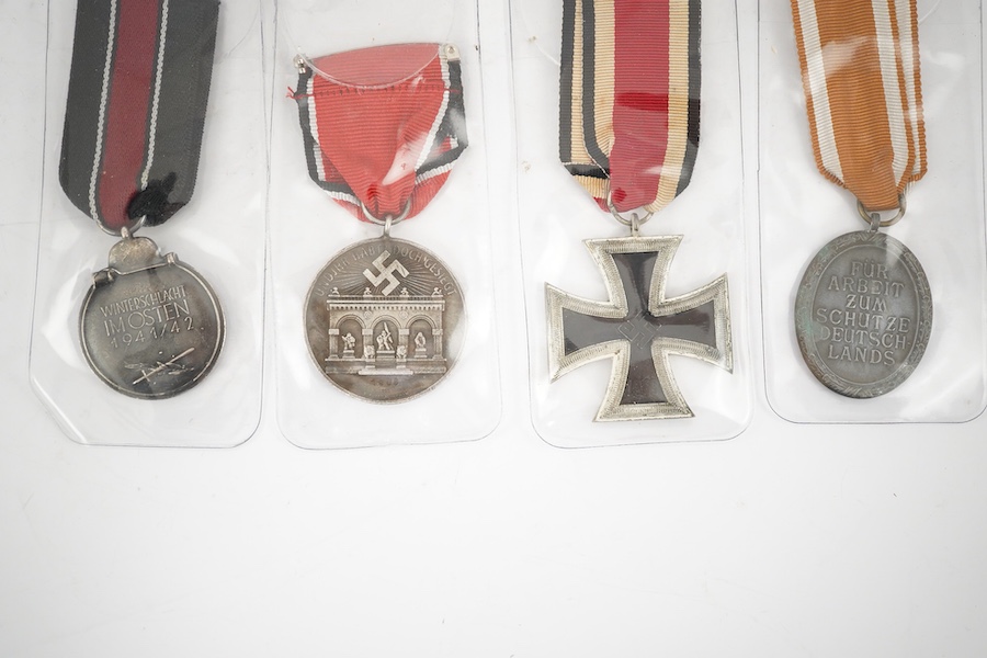 Nine German WWII medals; three Blood Order medals, a Second class Iron Cross, a War Merit medal in its original envelope, plus another unpacketed, a Second class War Merit cross, an Eastern Front Medal, and a West Wall M